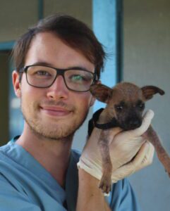 Volunteer holding a young rescued dog in his hand.